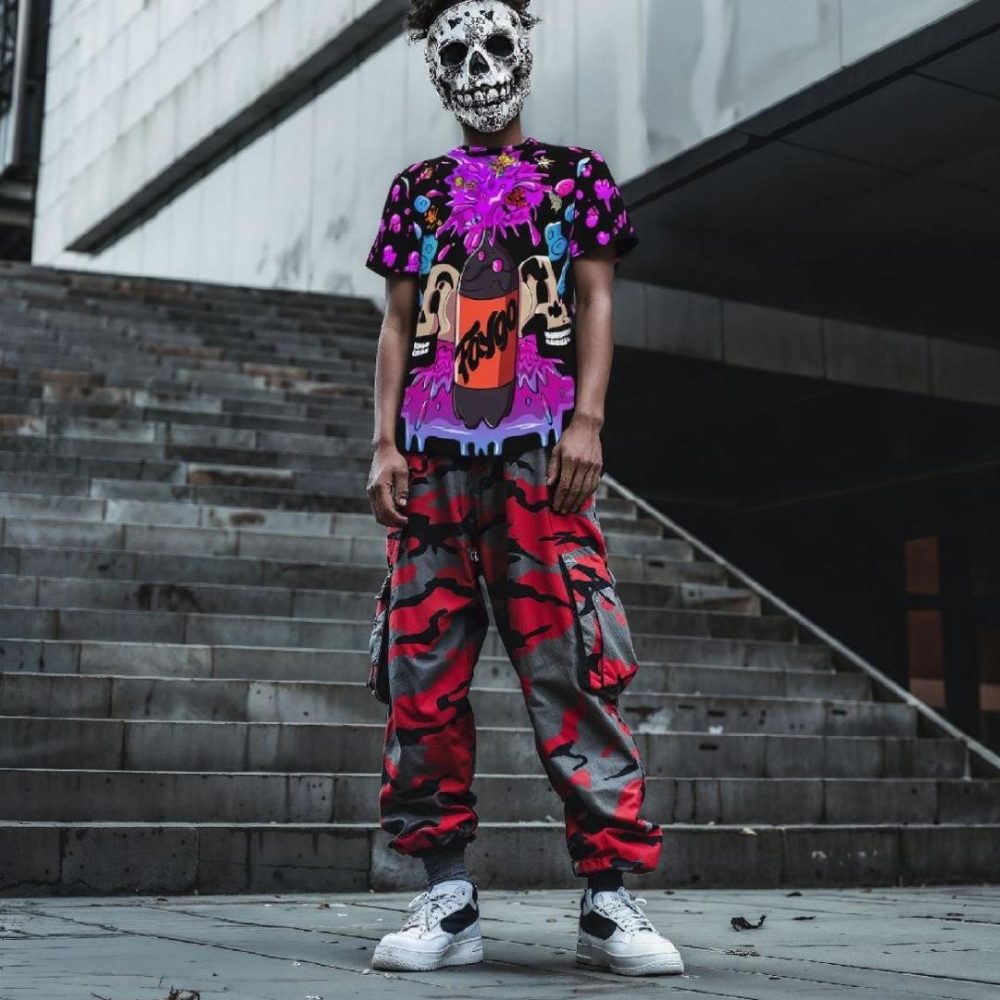 Juggalo wearing a skeleton mask and a Faygo Rain shirt, paired with red camouflage pants, standing in front of a city backdrop. The bold outfit represents streetwear style with a touch of underground culture.